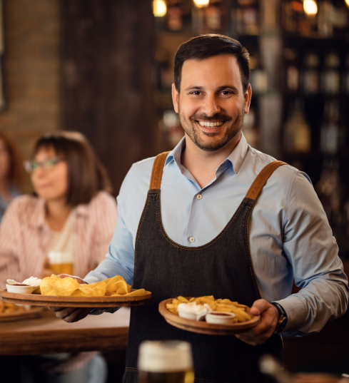 Happy waiter holding plates with food looking
